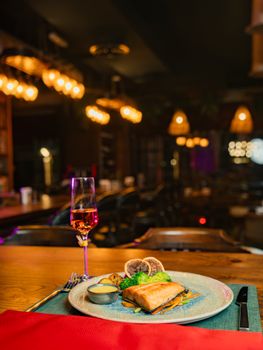 A beautifully plated dish with a glass of wine in a cozy Iraqi restaurant setting.