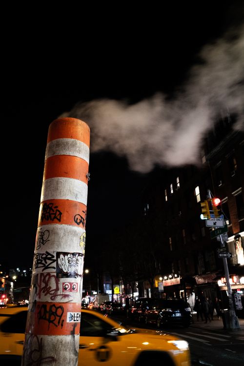 Free Graffiti-covered vent emitting steam at night in New York City. Stock Photo