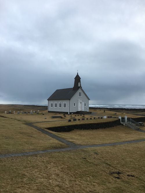 Free Charming white church amidst Iceland's landscape, under cloudy sky. Stock Photo