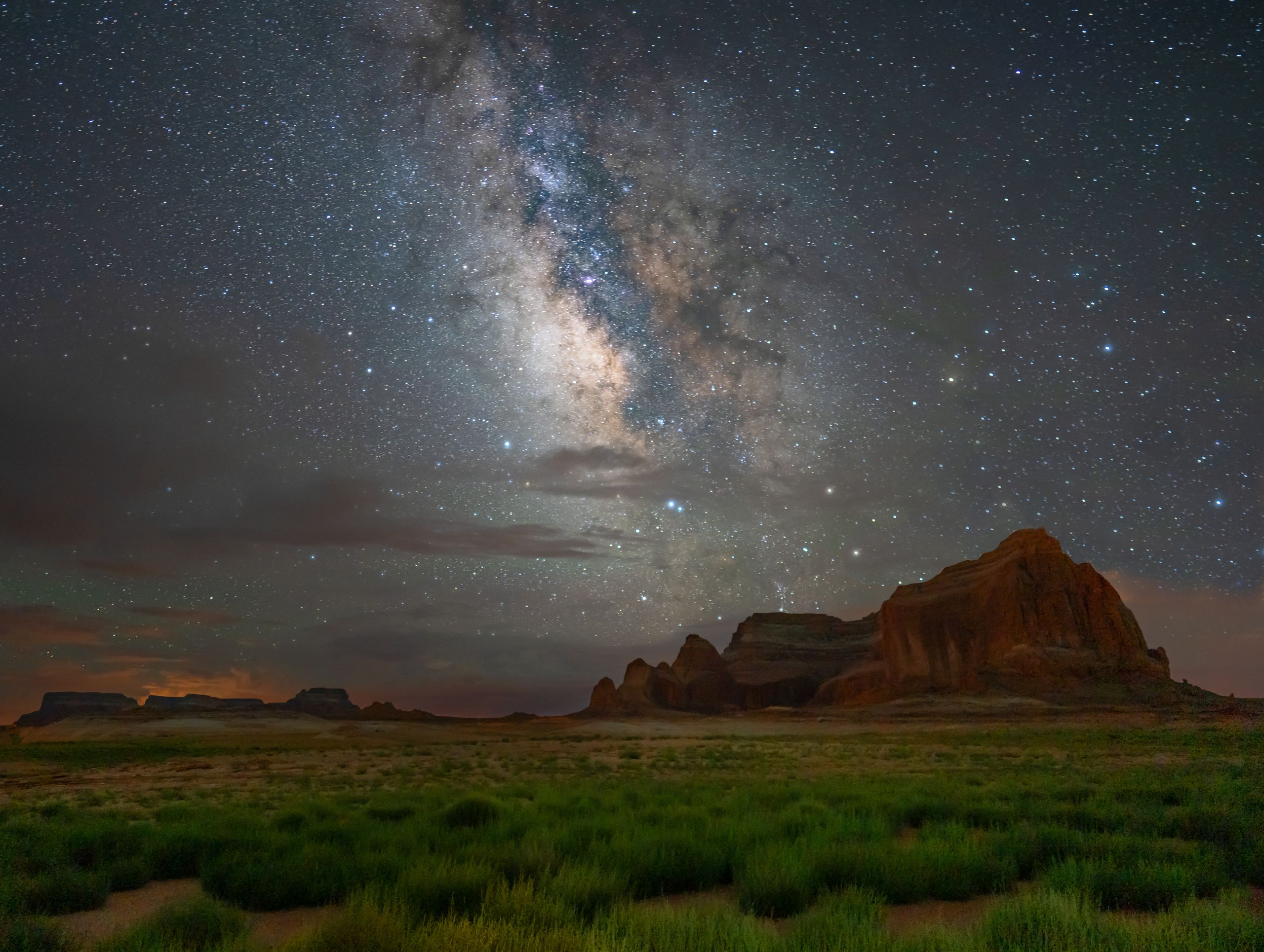 The Milky Way stretching across the night sky above an open desert landscape