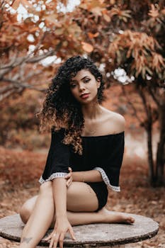一位卷发年轻女子在秋季的户外风景中摆姿势