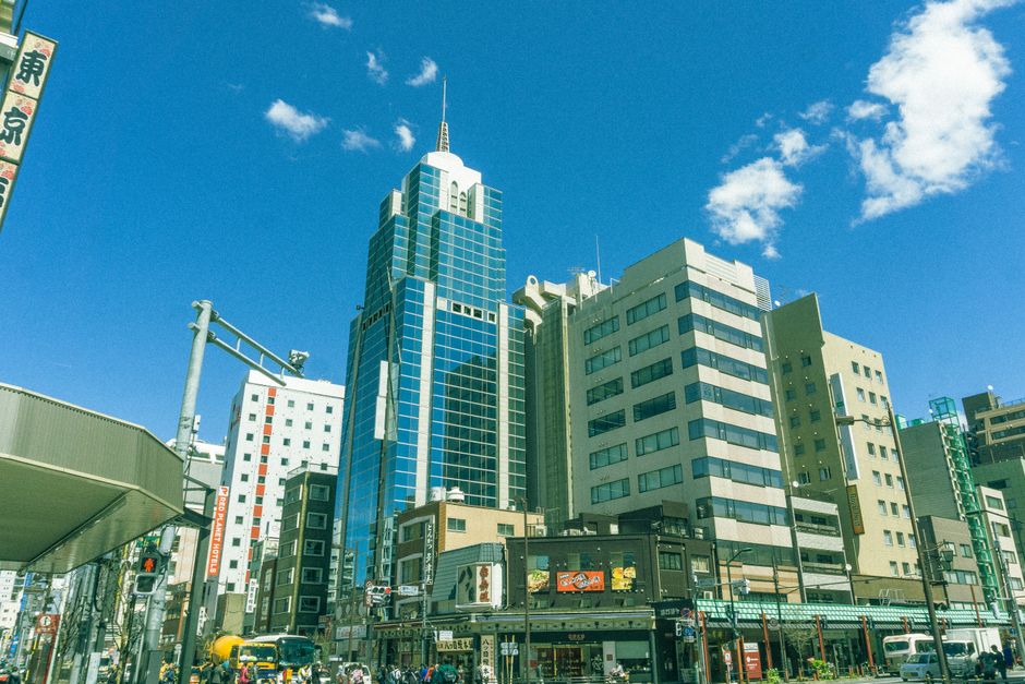 明るい青空の下、近代的な高層ビルが立ち並ぶ活気に満ちた東京の街並み。