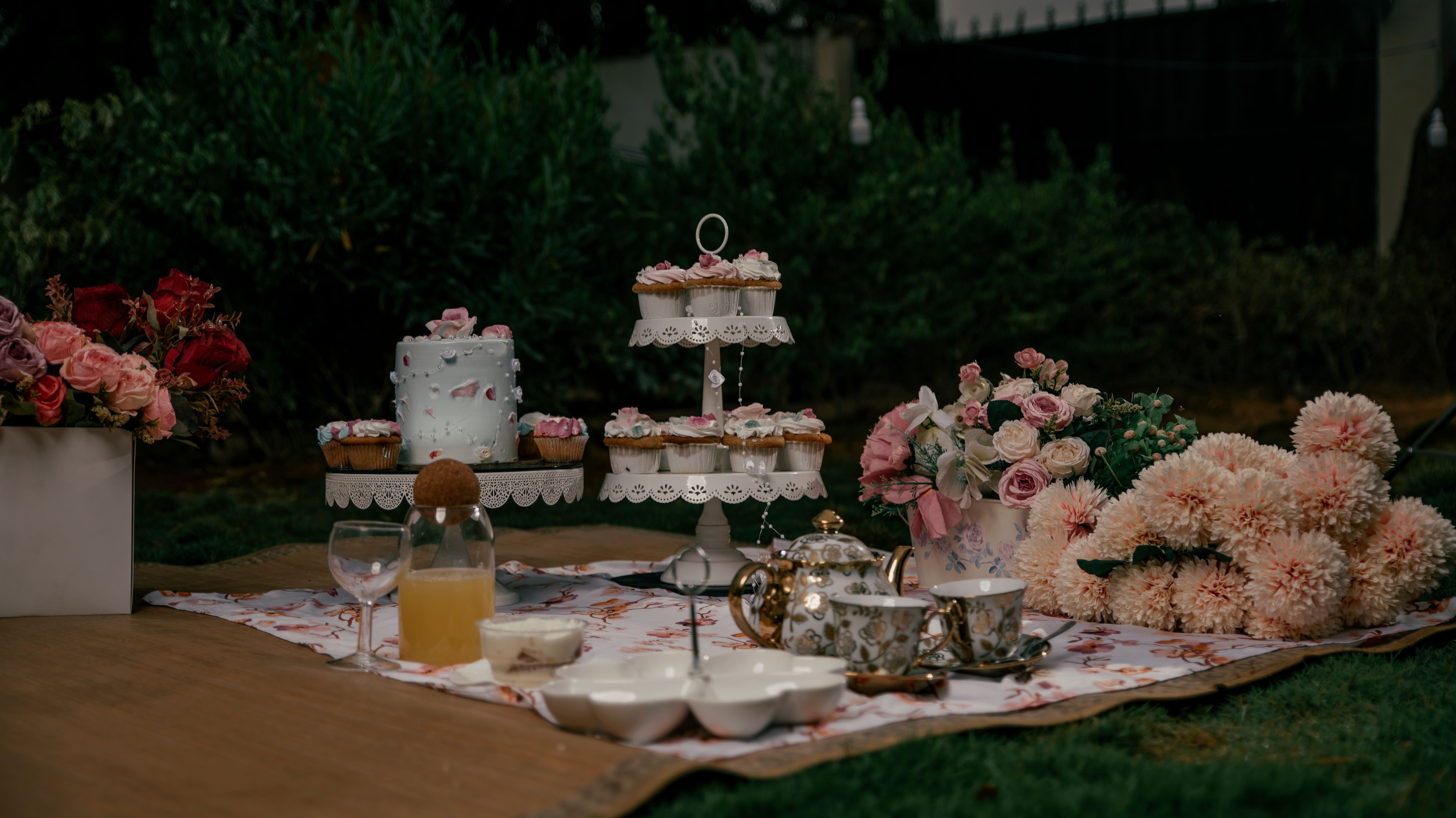An elegant outdoor afternoon tea table set with cakes, florals and vintage china.