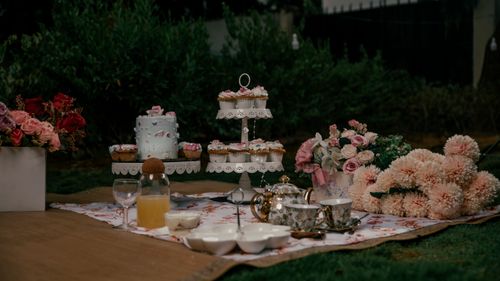 Free Charming outdoor tea party setting with elegant floral decorations, cupcakes, and vintage tea set. Stock Photo