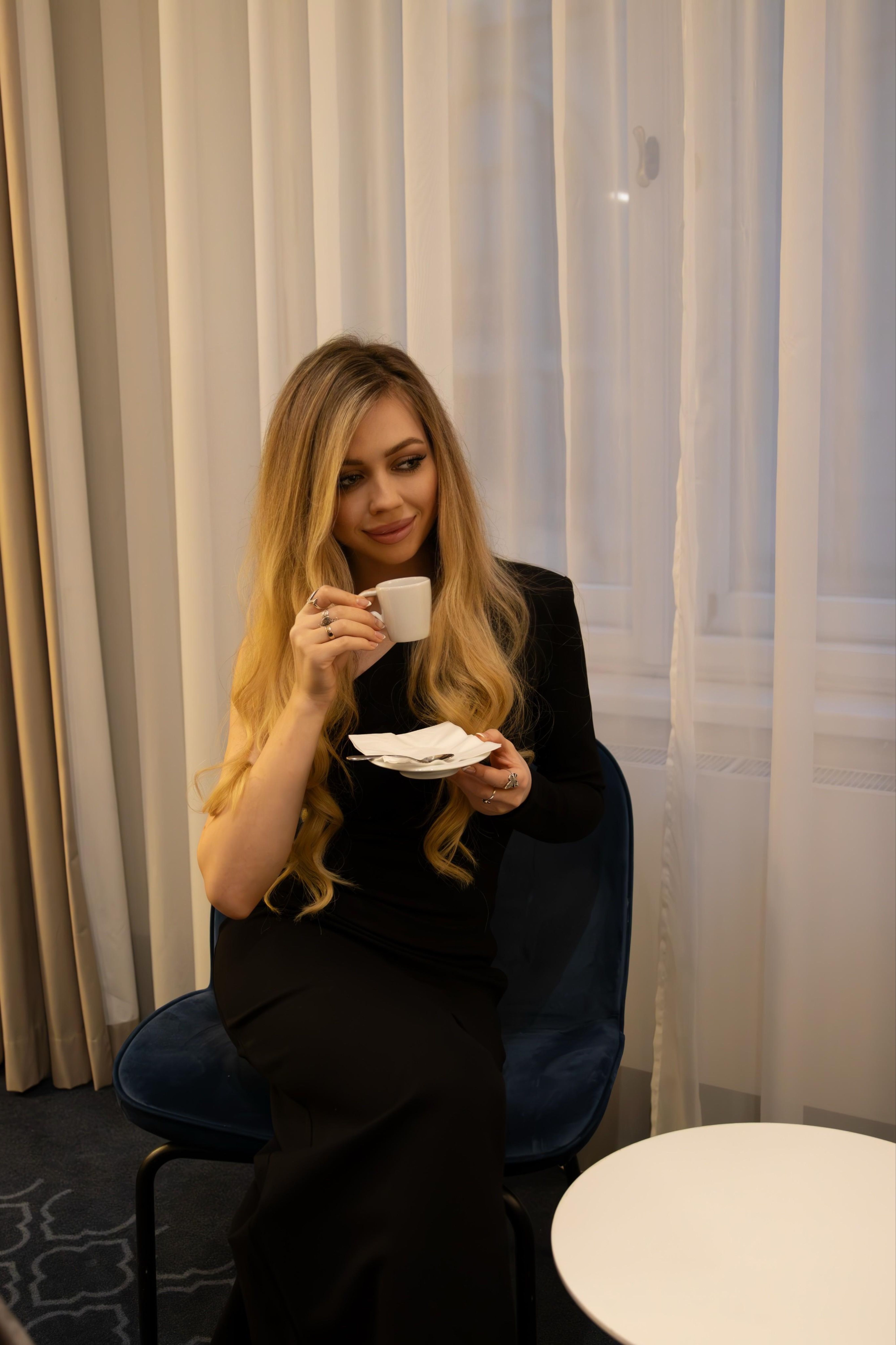 Stylish woman with long hair enjoying coffee inside a cozy room.
