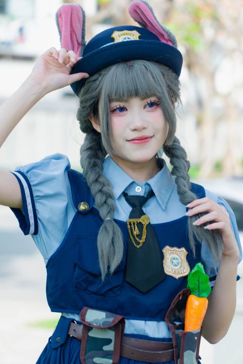 Free A young woman dressed in a playful police cosplay outfit with bunny ears smiling outdoors. Stock Photo
