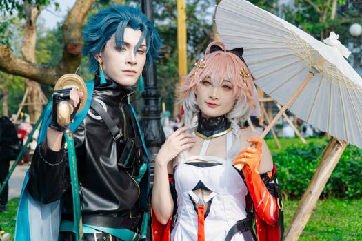 Two cosplayers in vibrant costumes posing with a parasol outdoors.