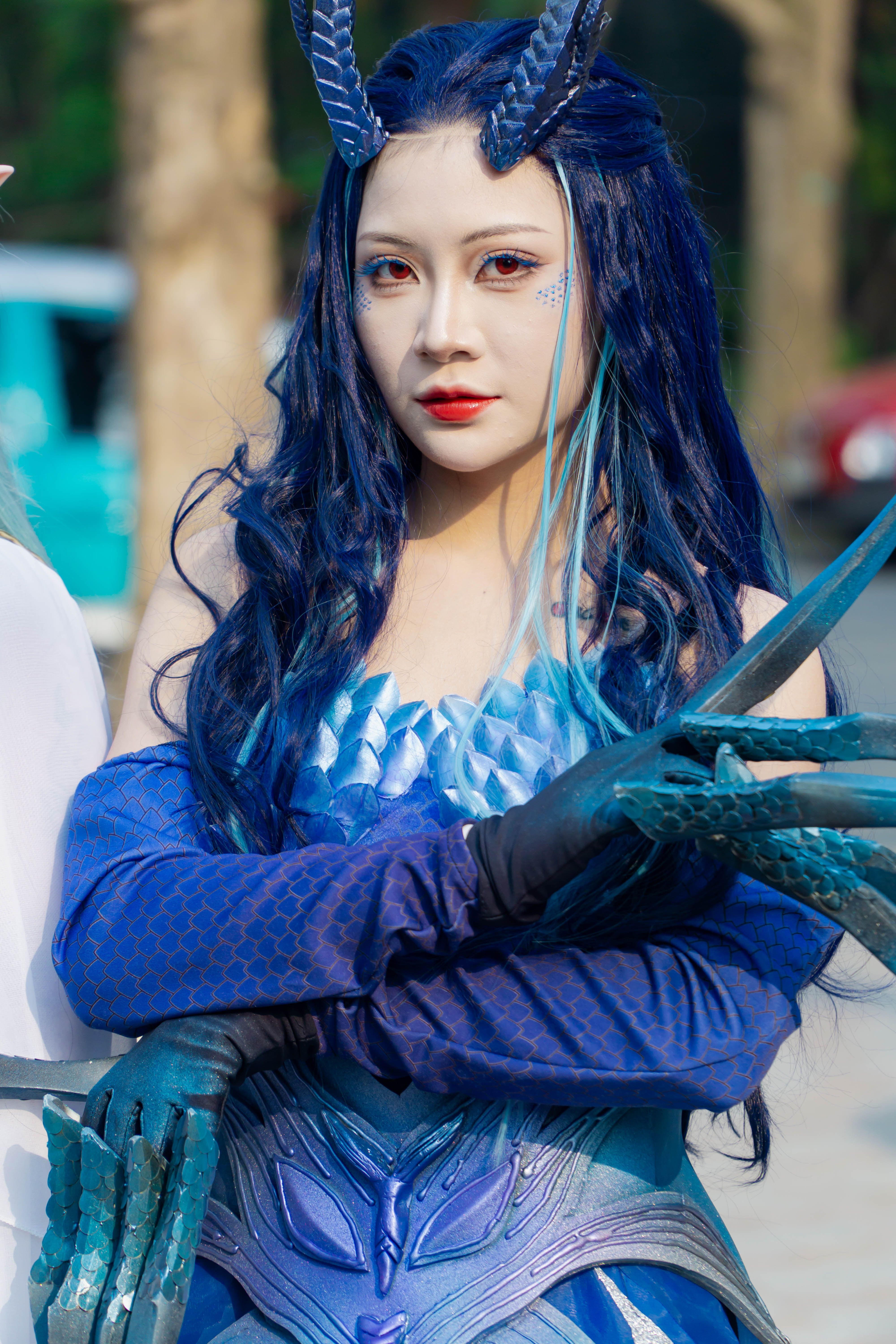 Woman in fantasy-inspired blue costume with intricate details outdoors.