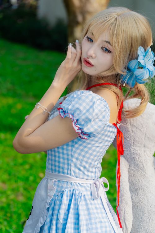 Free Young woman in a blue gingham dress with a bow and accessories, standing outdoors. Stock Photo