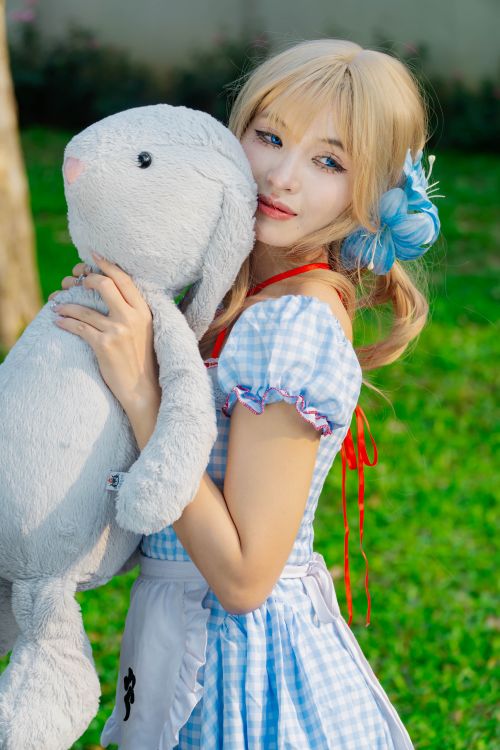 Free Young woman in cosplay costume holding a plush bunny in a garden setting. Stock Photo