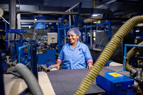 Free A woman working in a bustling textile factory, surrounded by machinery. Stock Photo