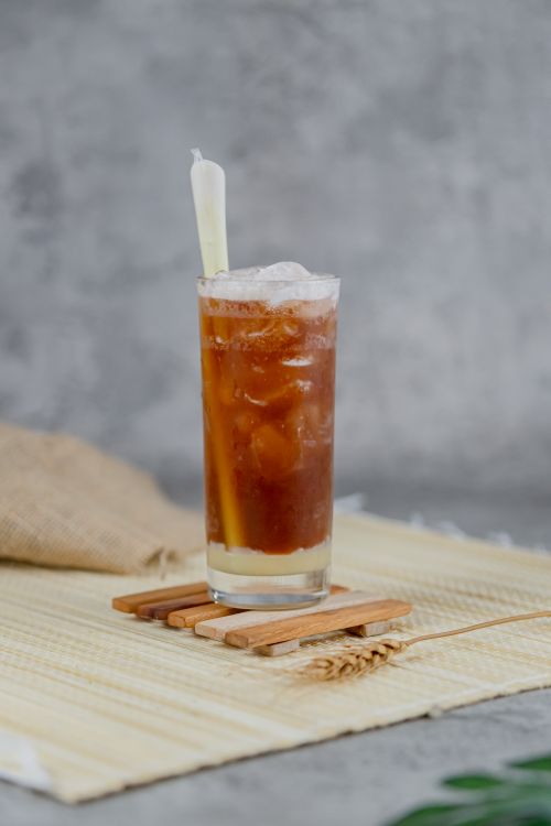 Free Chilled glass of iced tea with ice cubes and lemongrass in a serene setting. Stock Photo