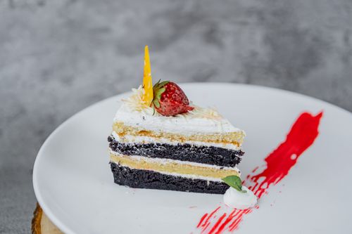 Free A delightful slice of layered chocolate and vanilla cake topped with a strawberry on a white plate. Stock Photo