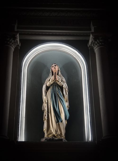 Free A beautifully illuminated Virgin Mary statue within a church setting. Stock Photo