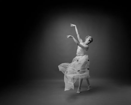 A graceful ballet dancer performs in a studio, captured in black and white.