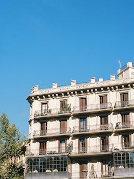 Elegant historic building with wrought iron balconies against a bright blue sky.