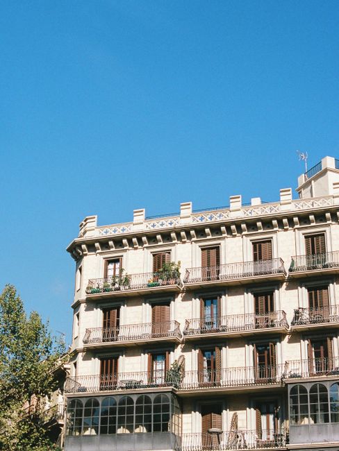 Elegant historic building with wrought iron balconies against a bright blue sky.