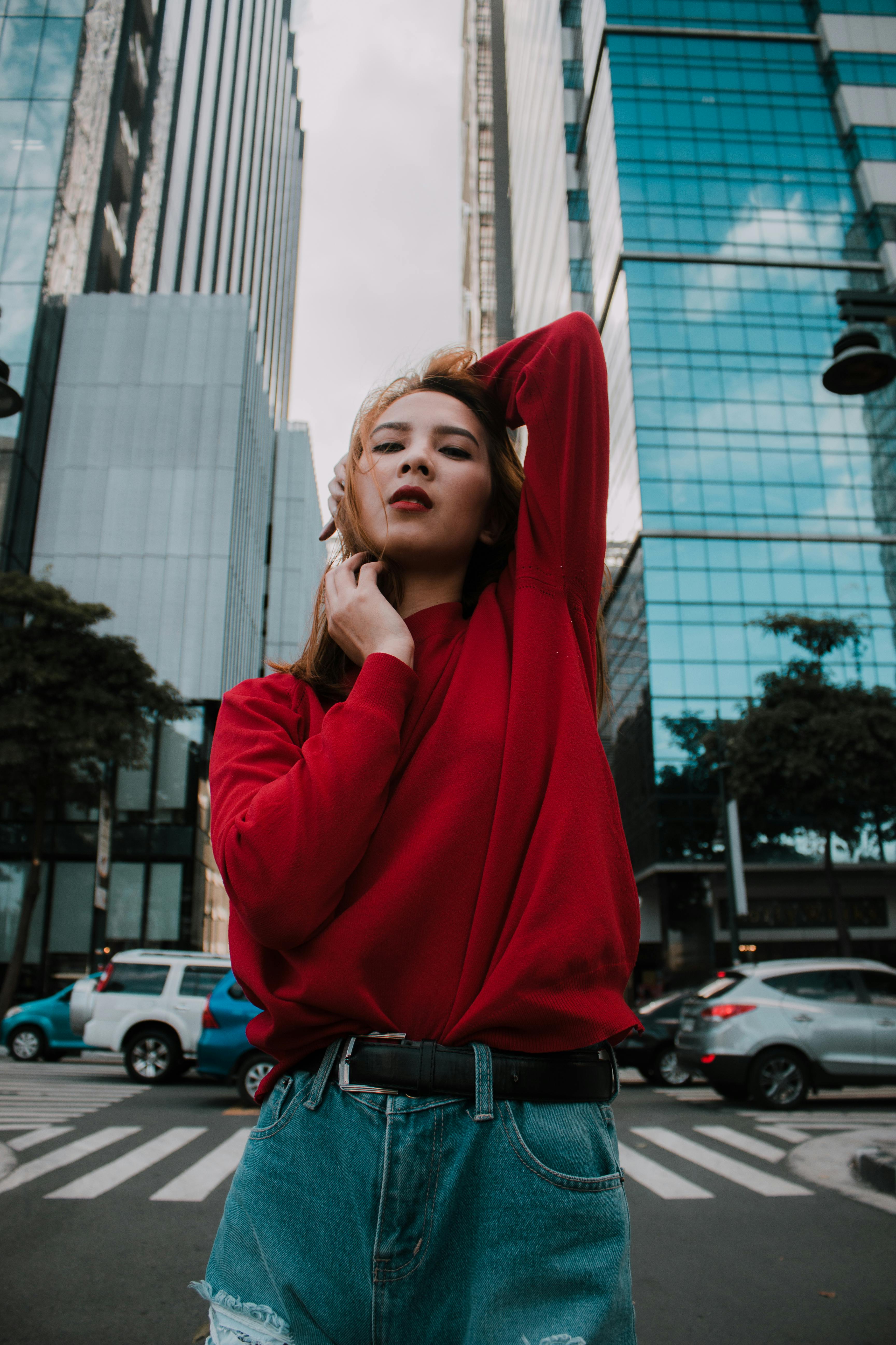 一位身着休闲服装的优雅年轻女子，在现代城市背景下自信地摆出姿势