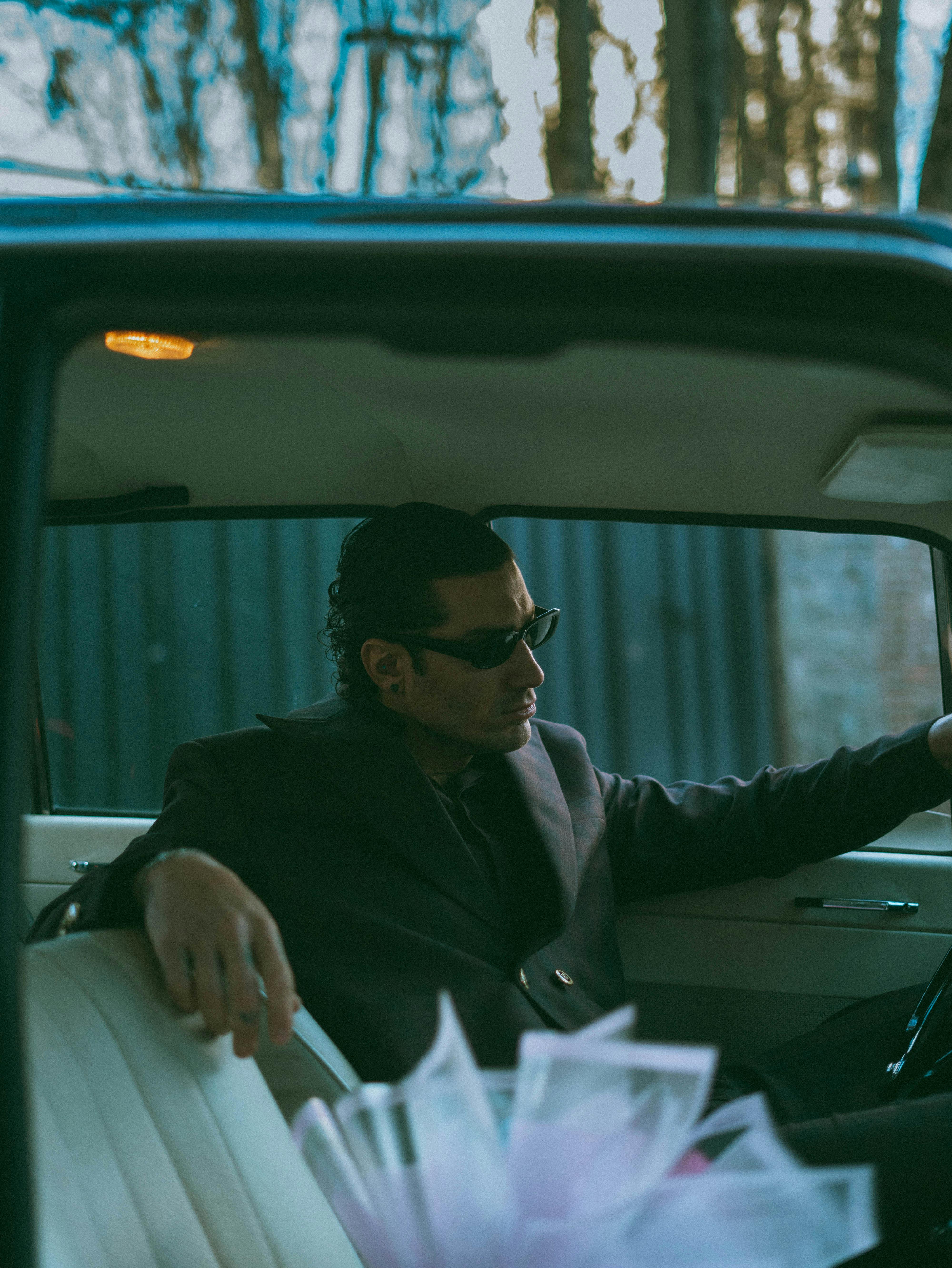 Gratis Un uomo con occhiali da sole siede con sicurezza in un'auto d'epoca, aggiungendo un tocco retrò alla scena. Foto a disposizione