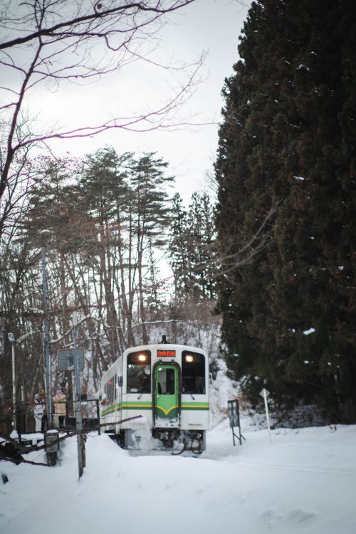 Free Green and white train traverses snowy landscape in Shimogo, Fukushima. Stock Photo