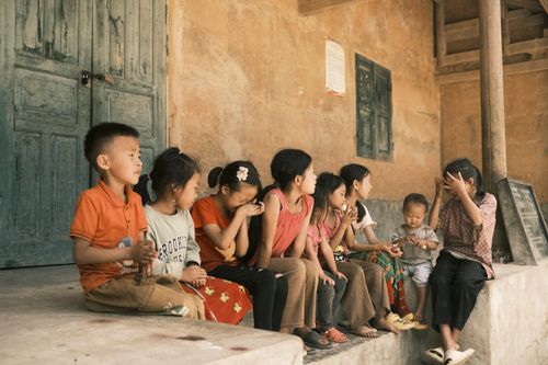 Free A group of children sitting on a rustic porch sharing a moment outdoors together. Stock Photo