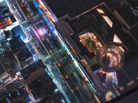 A vibrant aerial view of a busy city intersection at night, illuminated by colorful lights.