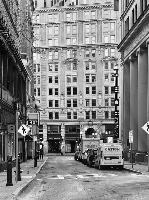 Free Black and white city street view with historic architecture and parked vehicles. Stock Photo