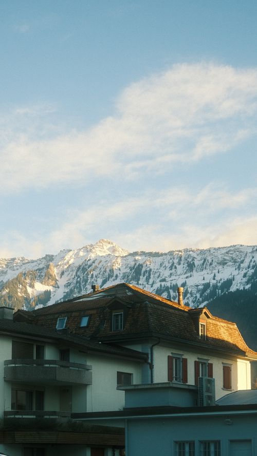Free Scenic view of a chalet-style house with snowy mountains in the background. Stock Photo