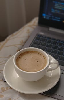 A cozy workspace featuring a cup of coffee placed on an open laptop, perfect for creative work.