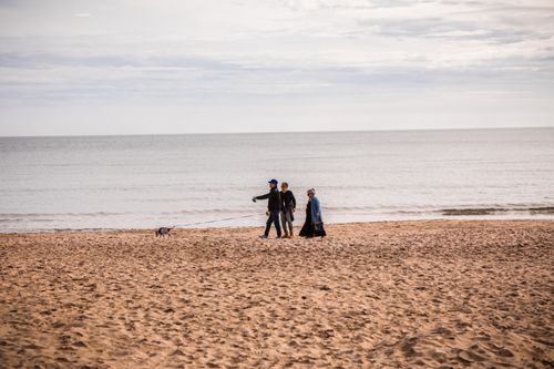 Free Family enjoying a walk with dog on Bournemouth beach, England. Serene seaside setting. Stock Photo