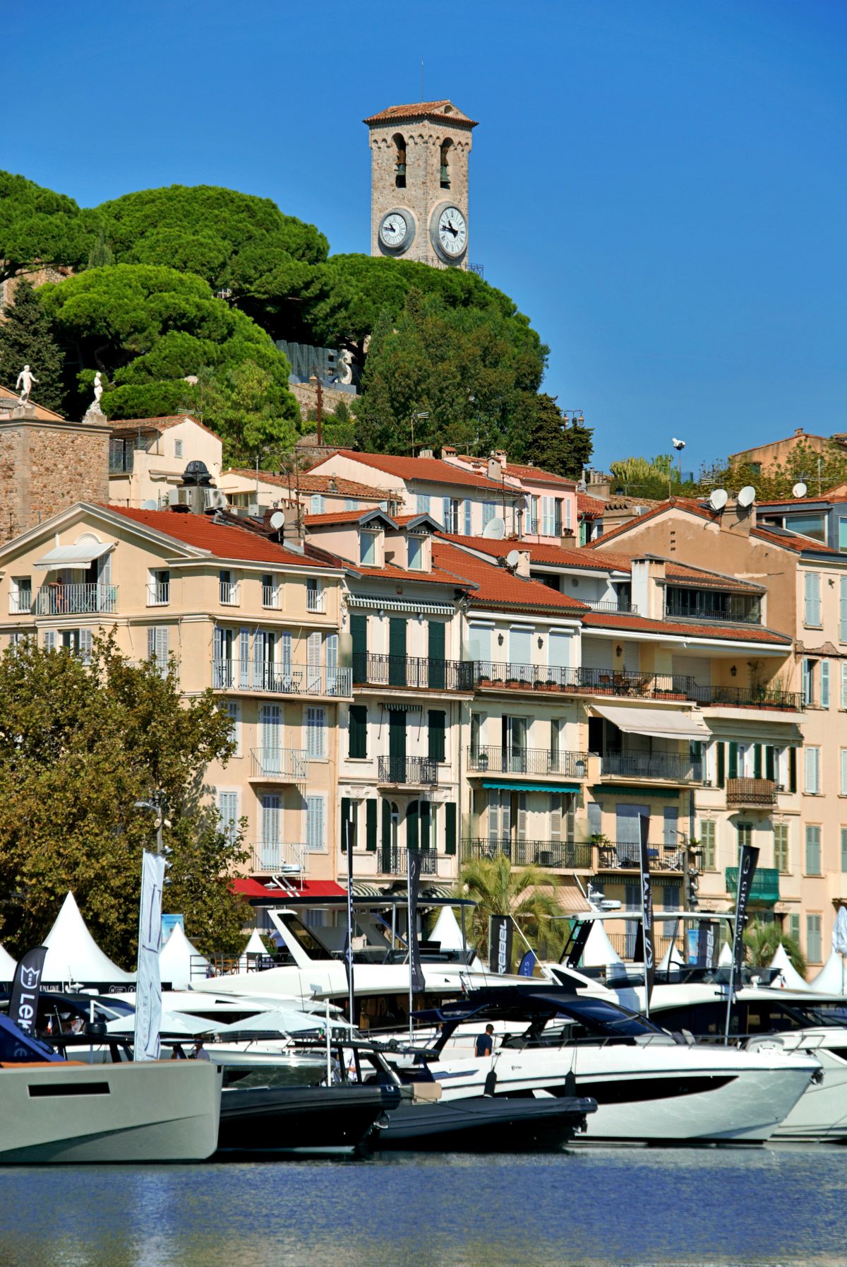 Yachts de luxe amarrés dans le port de Cannes, tour de l'horloge en arrière-plan