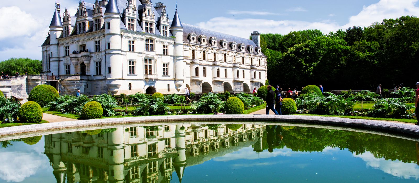 Beautiful reflection of Chateau de Chenonceau over water in France's lush gardens.