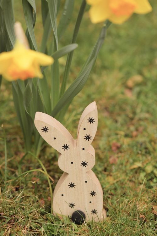 Free Wooden bunny decor in a grassy meadow with blooming daffodils, perfect for Easter. Stock Photo