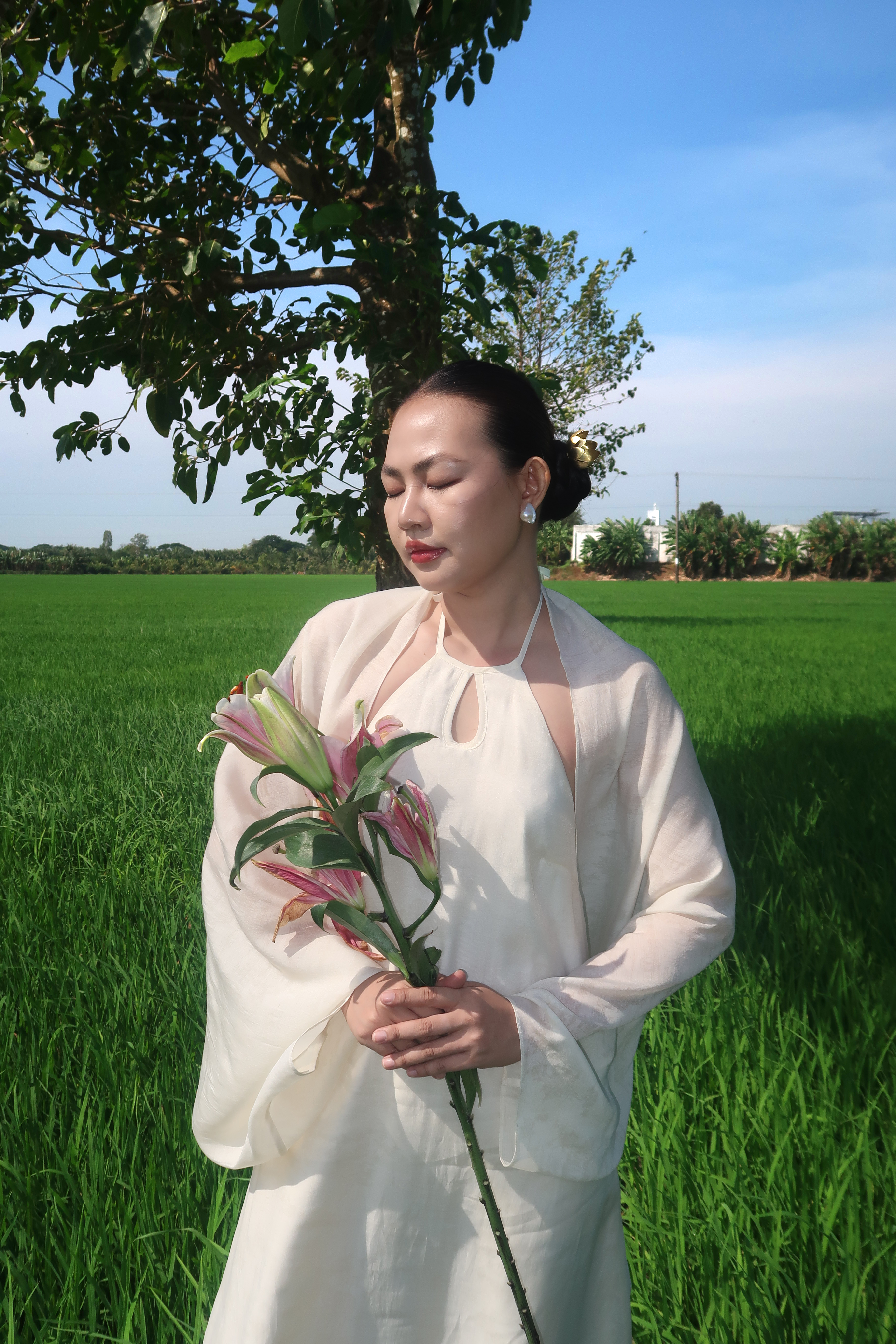 Woman in Elegant Attire Holding Lilies Outdoors · Free Stock Photo