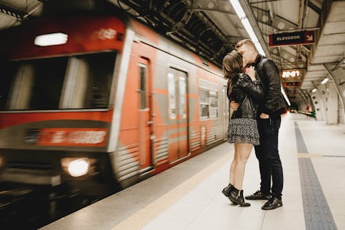 Free Kissing Couple Beside Running Train in Subway Stock Photo