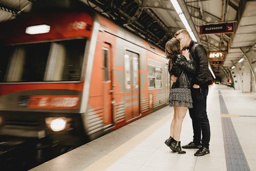 Couple sharing a romantic kiss on a subway platform as a train arrives.