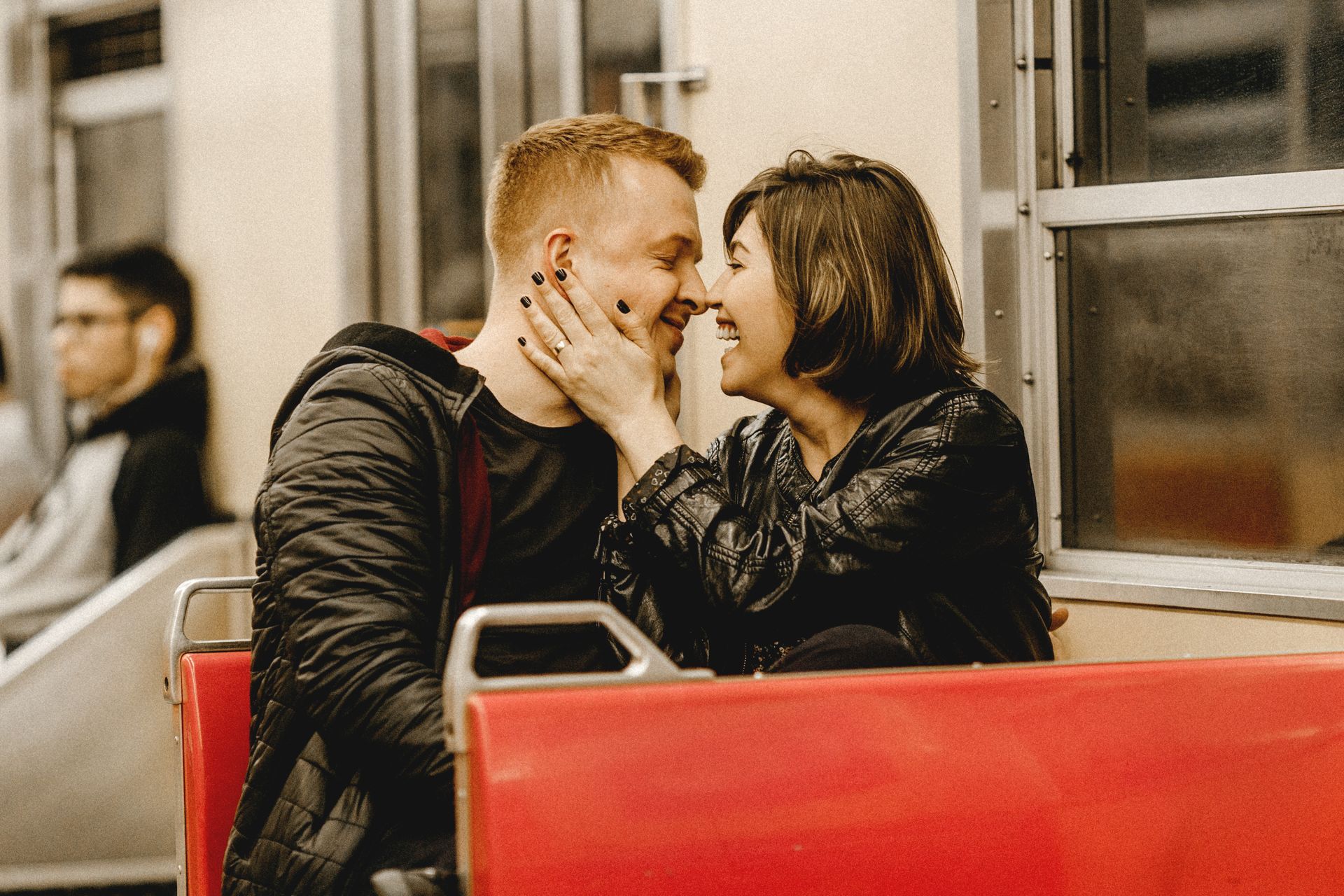 A happy couple embracing and laughing on a public transport seat, capturing love and connection.