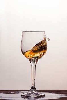 A clear glass with swirling amber liquid against a soft background.