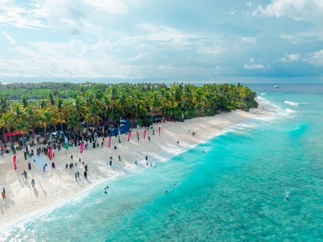 A vibrant scene of people gathering on a tropical beach in Fuvahmulah, Maldives.