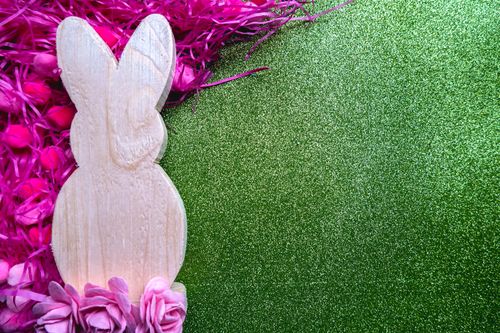 Free Wooden Easter bunny silhouette with pink floral accents on a glittering green background, perfect for festive decor. Stock Photo