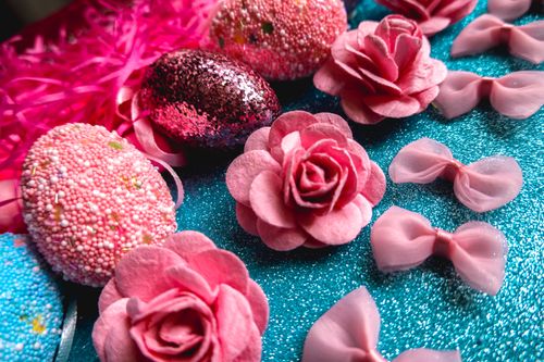 Free Vibrant Easter scene with decorative eggs, pink flowers, and ribbons on a sparkling background. Stock Photo
