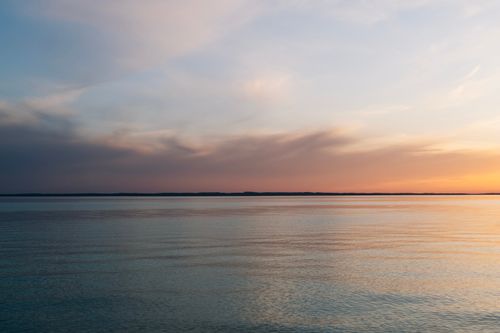 Free Calm waters of Lake Michigan reflecting a vibrant sunset sky with gentle clouds. Stock Photo