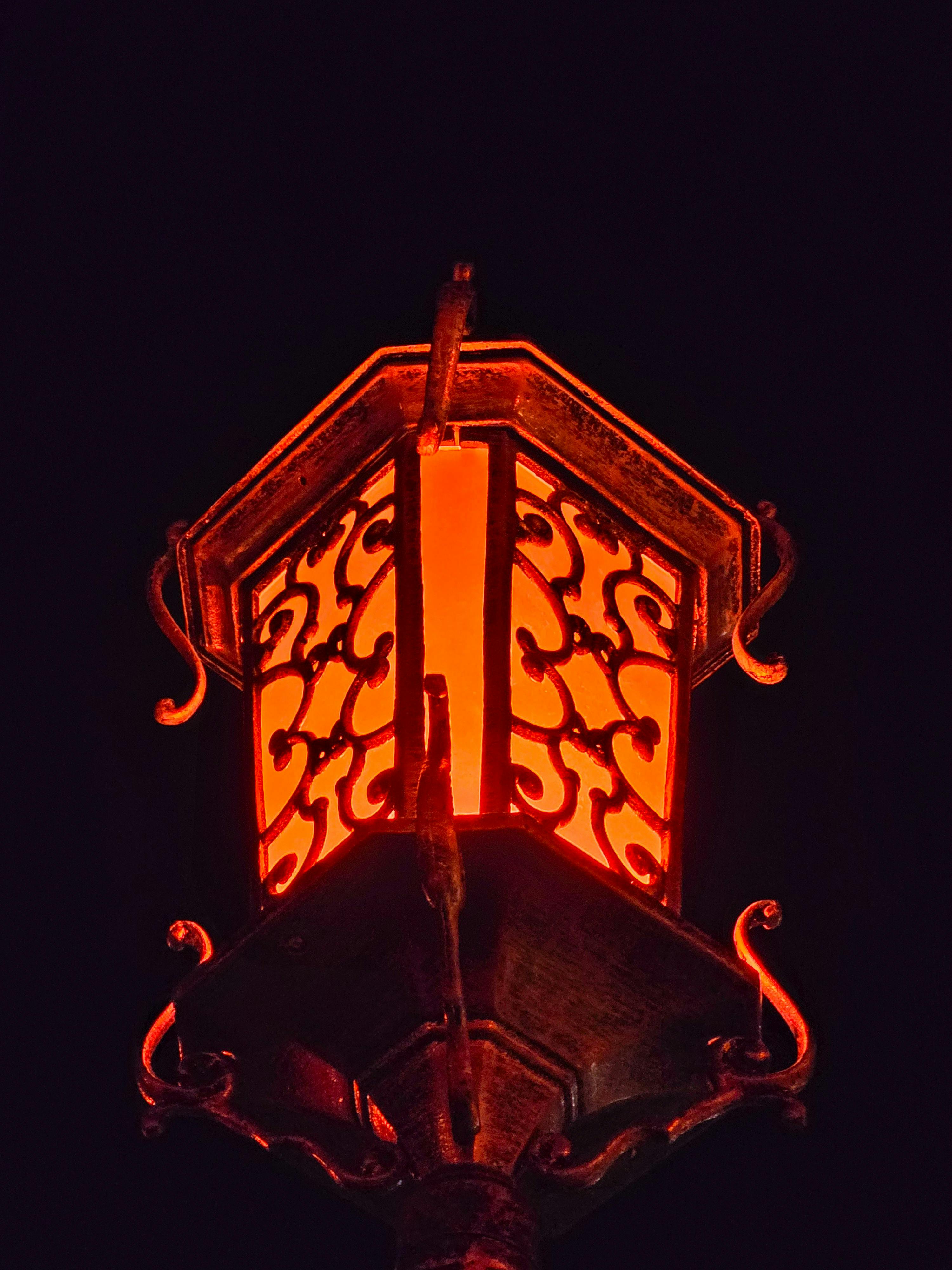 Zadarmo Zdobená vintage pouličná lampa s teplou žiarou proti tmavej nočnej oblohe, ktorá vytvára dramatickú atmosféru. Fotka z fotobanky