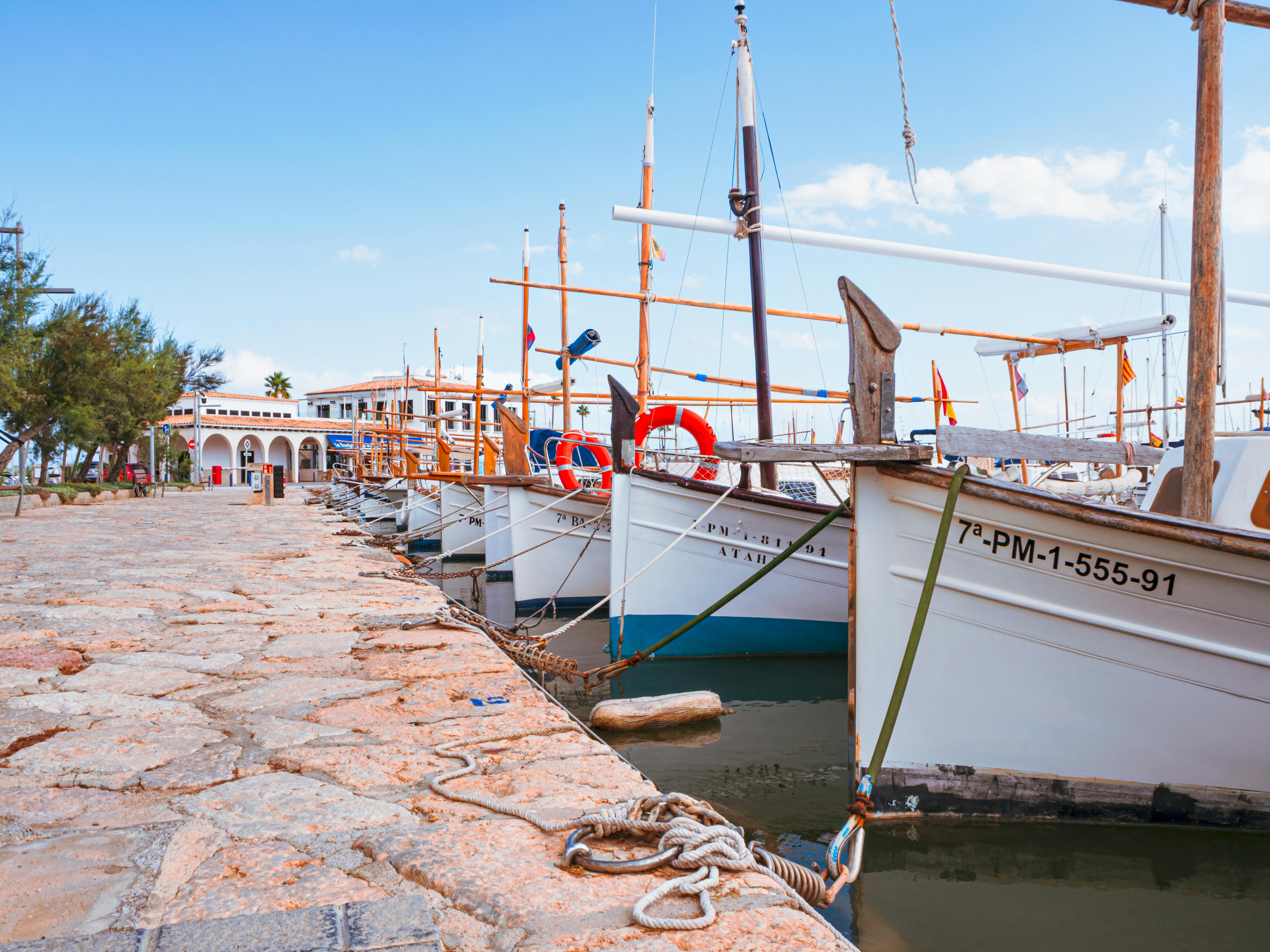 Serene marina with moored boats on a sunny day in Ibiza, Spain, featuring blue skies and tranquil waters.