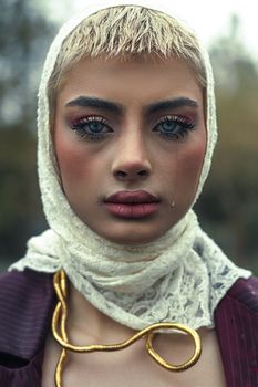 Detailed close-up portrait of a woman wearing a lace headscarf and gold accessories.