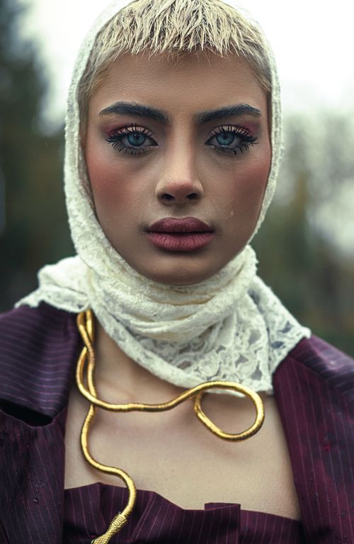 Free A striking outdoor portrait of a fashionable woman in bold, modern attire featuring intricate makeup and unique styling. Stock Photo