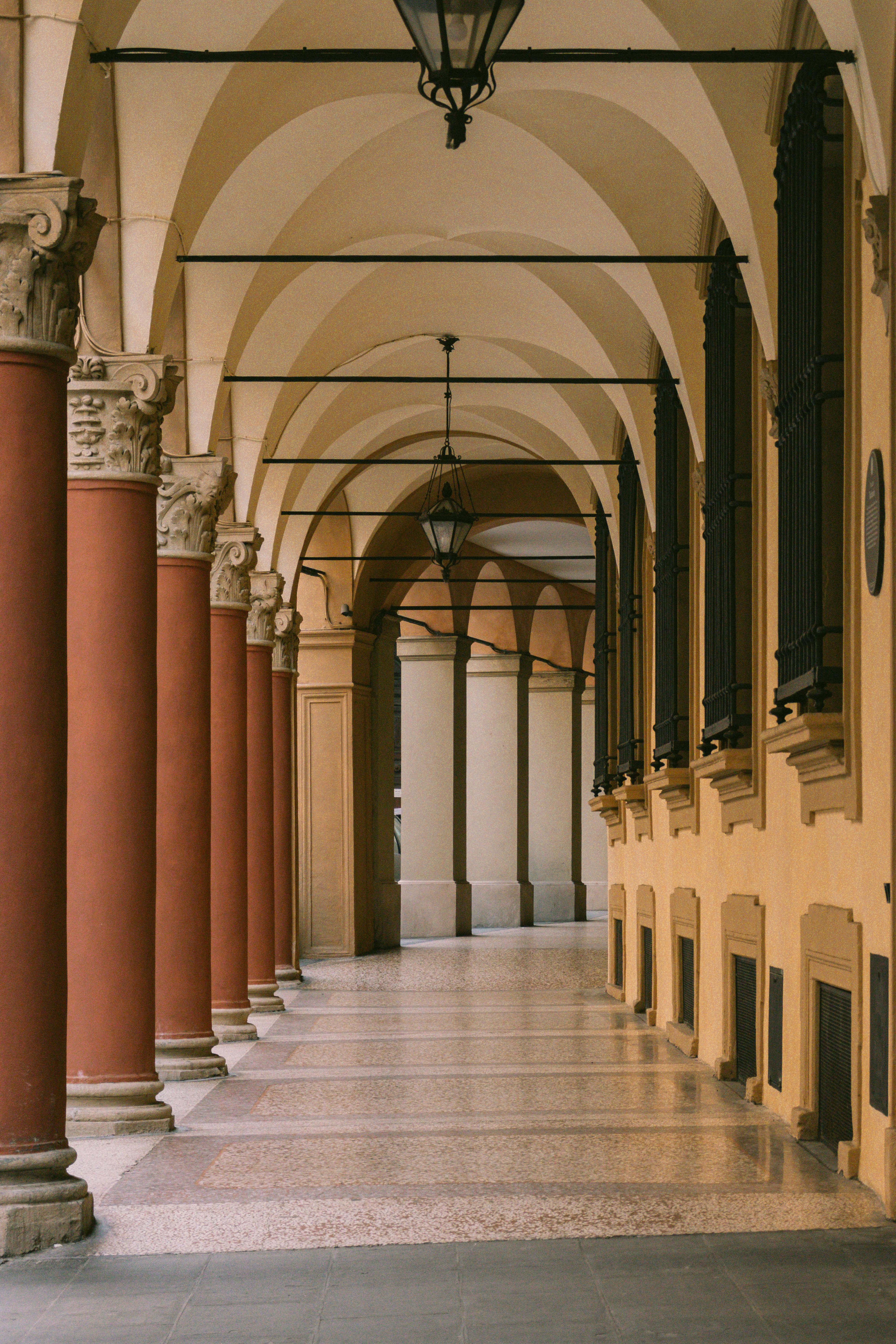 Elegant arched corridor with red columns and ornate architecture, capturing timeless beauty.