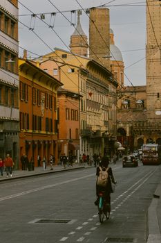 Cyclist rides through bustling street in Bologna, showcasing vibrant architecture.