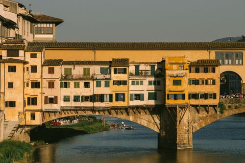 Free Ponte Vecchio in Florence glowing in golden hour sunlight over the Arno River. Stock Photo