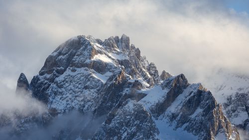 Free Stunning view of snow-covered peaks in the Dolomites under a cloudy sky, captured at sunrise. Stock Photo